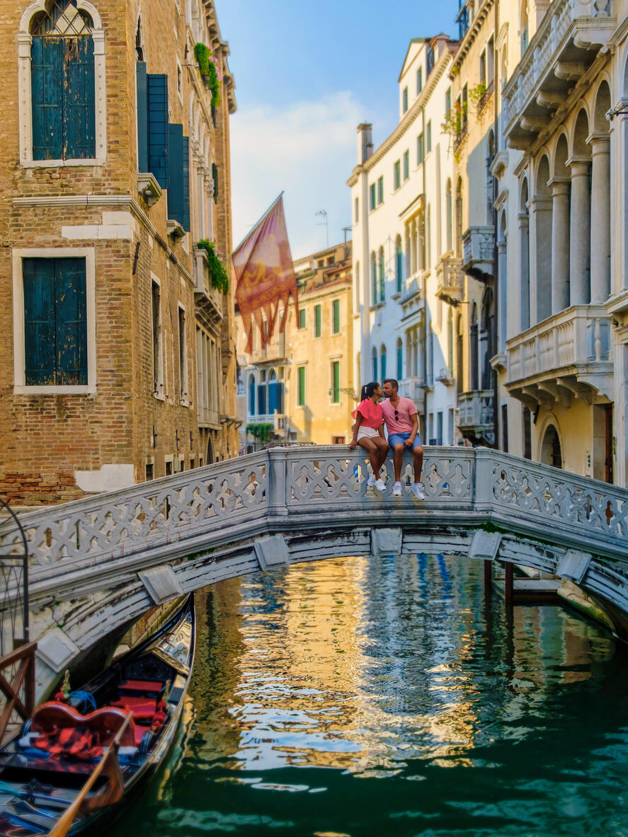 couple men and women on a city trip in Venice Italy sitting at a bridge above the canals of Venice